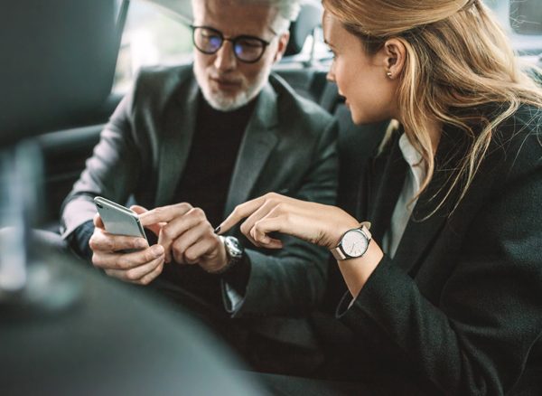 Business travellers in backseat of rideshare vehicle car using CTM mobile