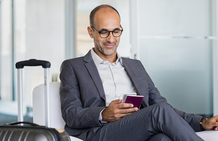 Business traveller sitting in airport lounge holding his phone and passport
