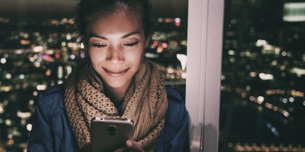 Business traveller in front of hotel room window at night using CTM Mobile app