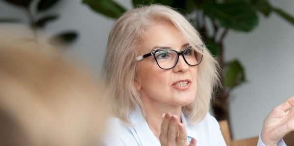 Mature female Travel Manager in glasses speaking at a meeting