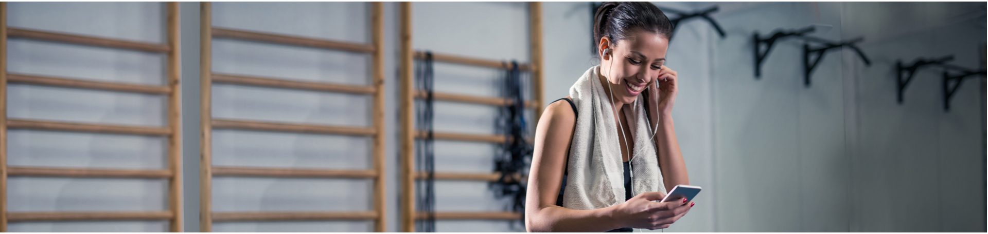 Woman in a gym with headphones in talking on phone