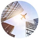 Business Travel News - December - worms eye view of a plane flying over a city