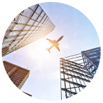 An upward shot of a plane flying over a city with high-rise buildings